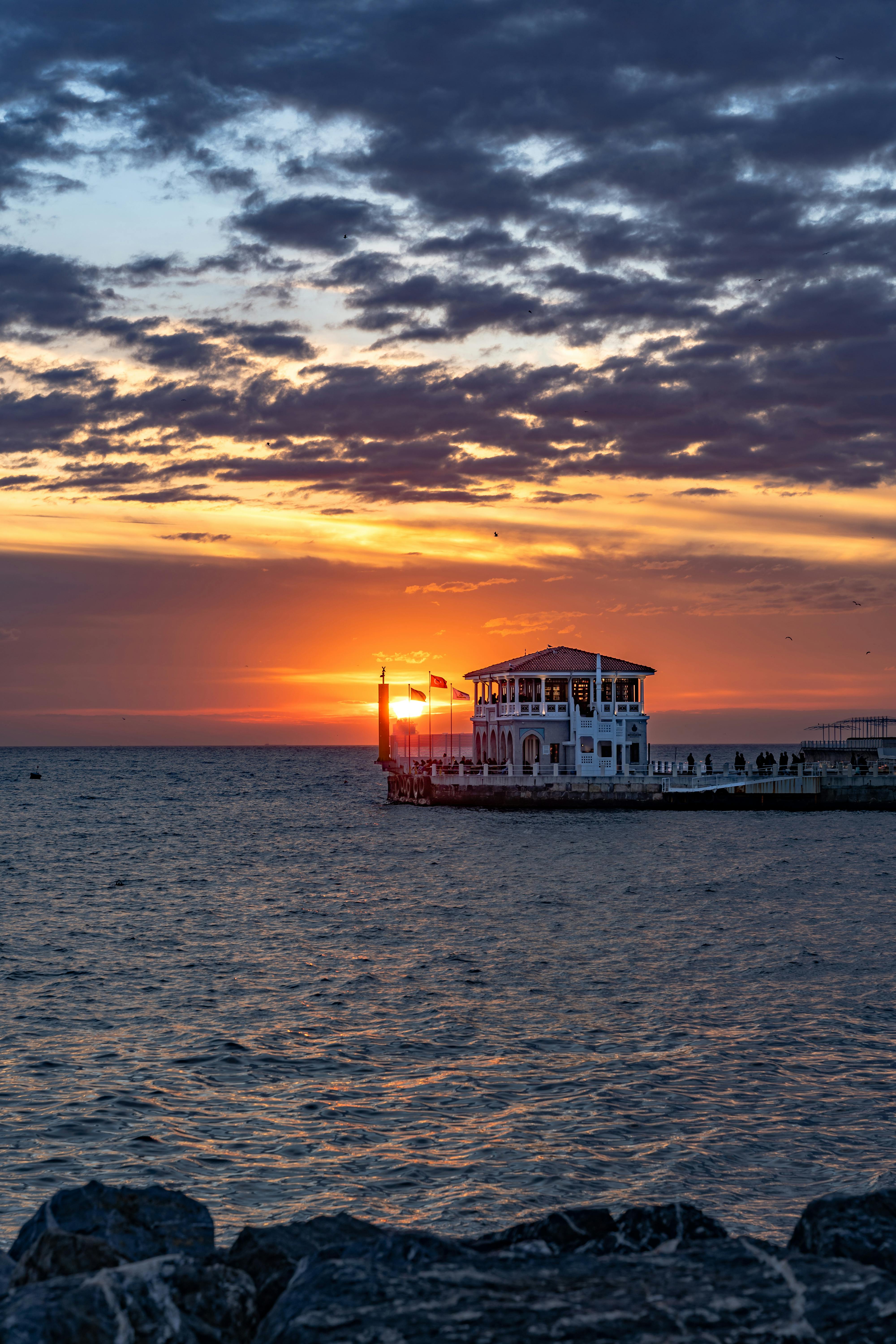 Gratis Livlig solnedgang over Moda Pier, Kadıköy med dramatiske skyer og fredelig havutsikt. Arkivbilde
