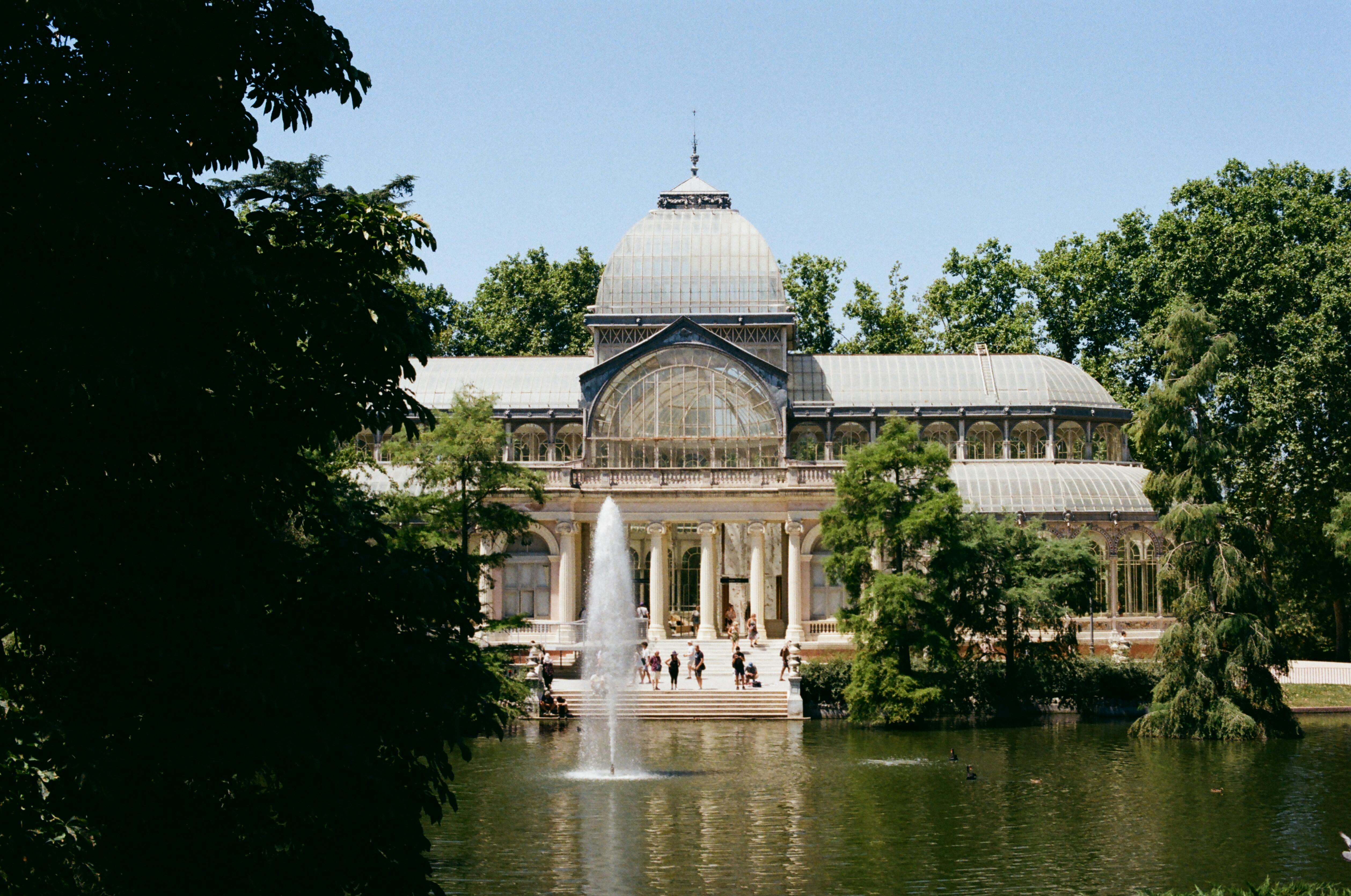 Stunning view of Crystal Palace in Retiro Park, Madrid, surrounded by lush greenery.