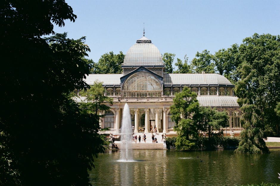 Stunning view of Crystal Palace in Retiro Park, Madrid, surrounded by lush greenery.
