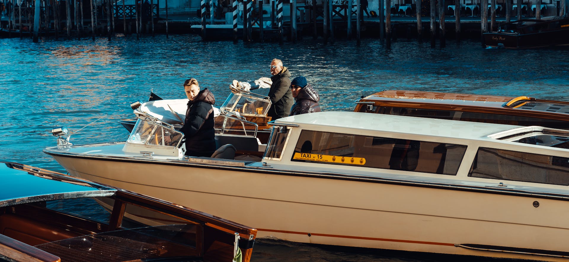 Three adults on a water taxi navigating a scenic canal, capturing a lively urban setting.