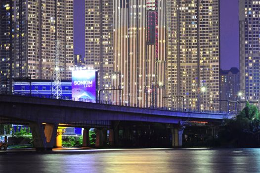 A dazzling view of a bridge with the illuminated skyline of Ho Chi Minh City at night.