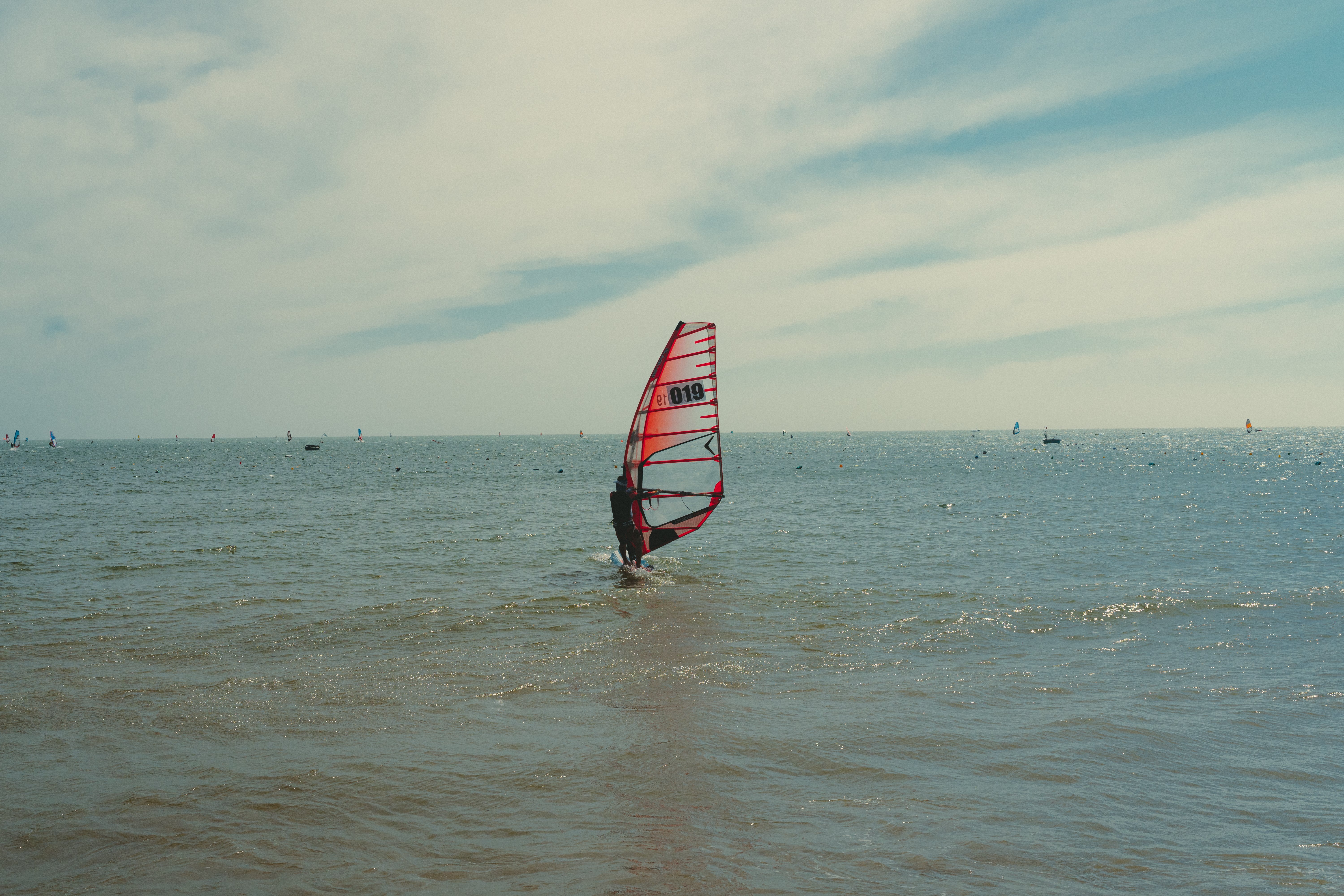 A windsurfer glides over the calm sea in Phan Thiet under a clear sky.