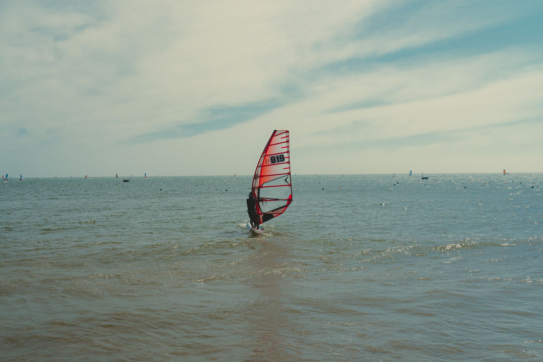 A windsurfer glides over the calm sea in Phan Thiet under a clear sky.