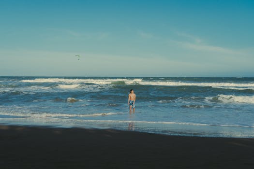 A serene scene of a man enjoying the waves at Phan Thiet Beach in Vietnam.