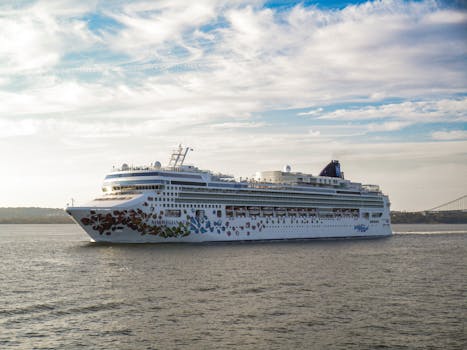 A large cruise ship gracefully sails on a calm sea under a bright sky.