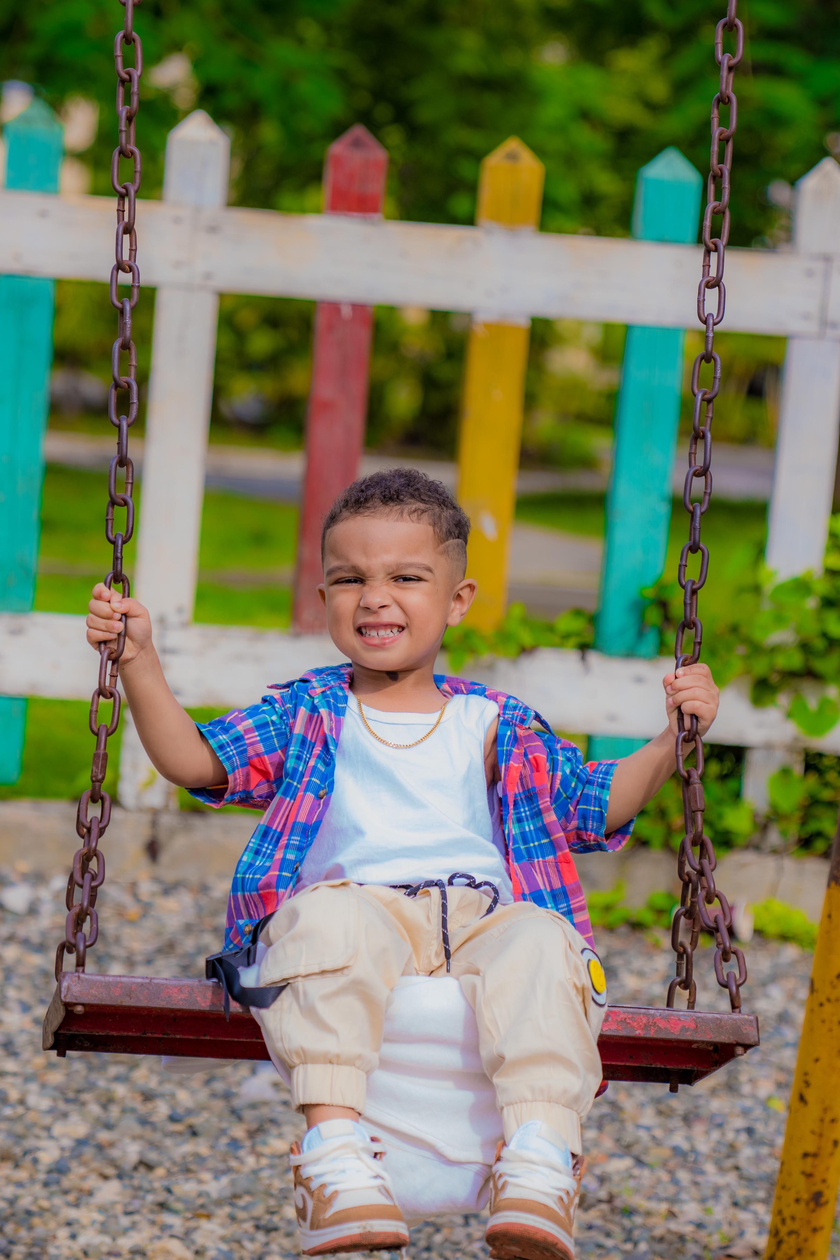Smiling child enjoys a swing in a colorful park setting, radiating joy and playfulness.