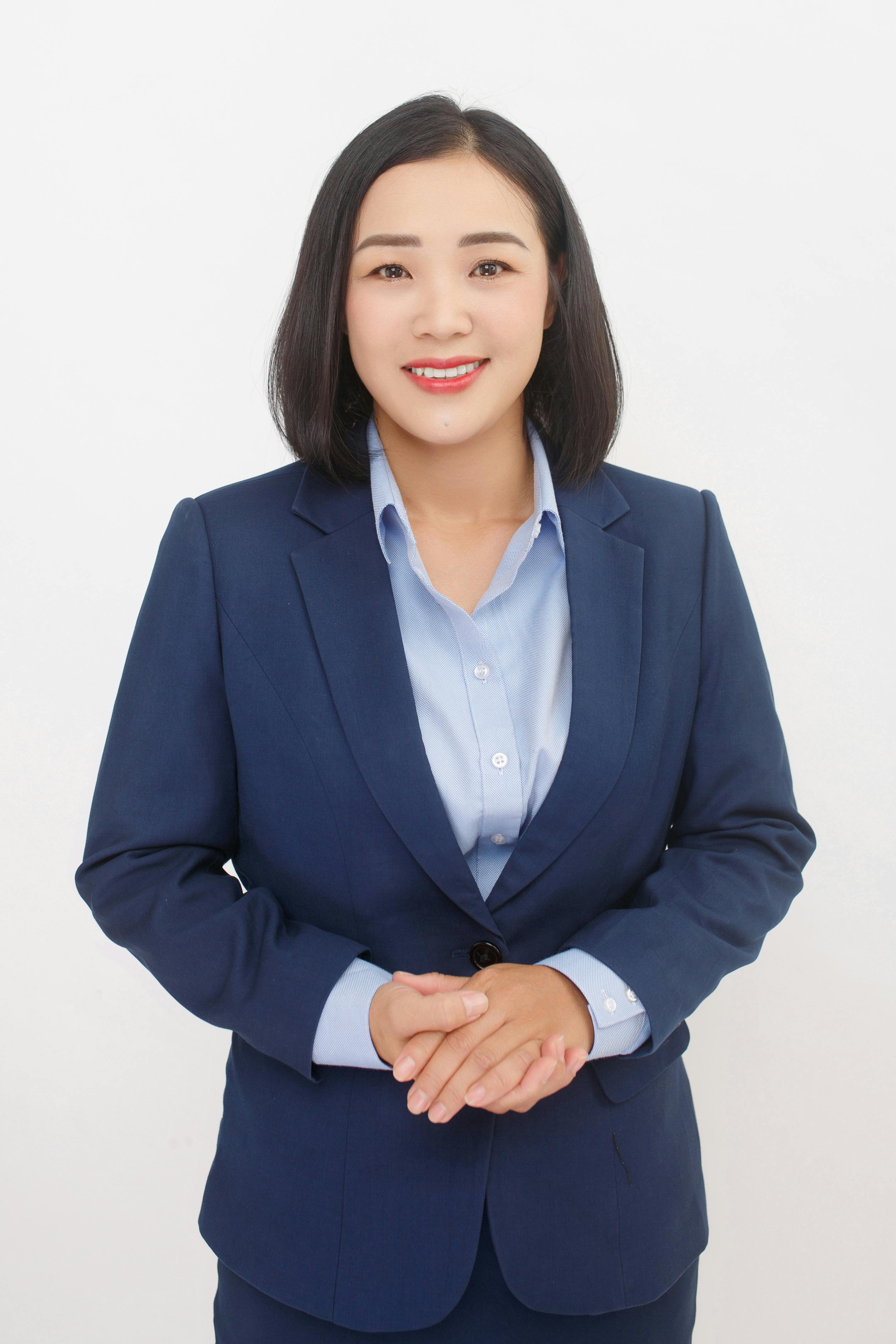 Portrait of a confident business woman in a navy suit and blue shirt, smiling.