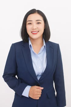 Confident businesswoman in a blue suit with a welcoming smile, posing against a white background.