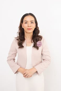 Elegant businesswoman in a light pink blazer posing against a clean white background.