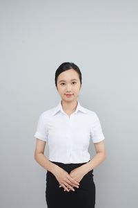 Presenter in formal attire against a plain backdrop, by Tran Nhu Tuan on Pexels