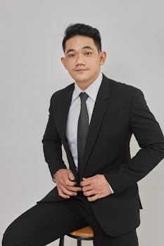 Portrait of a young man in a suit, seated, exuding confidence and professionalism.