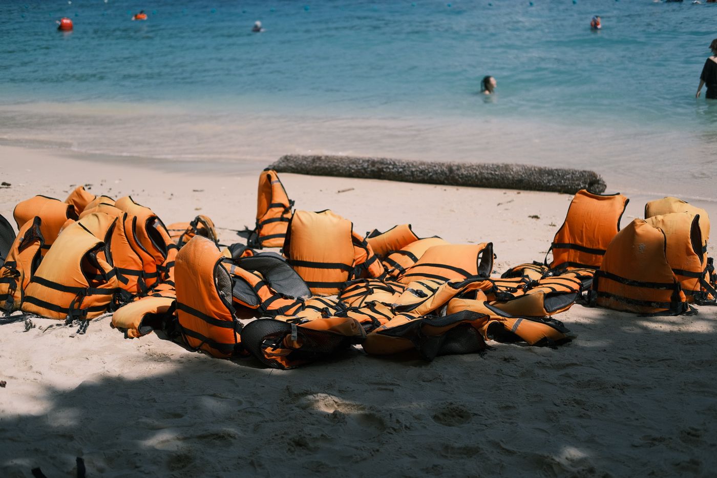 Bright life jackets arranged on a sunny beach