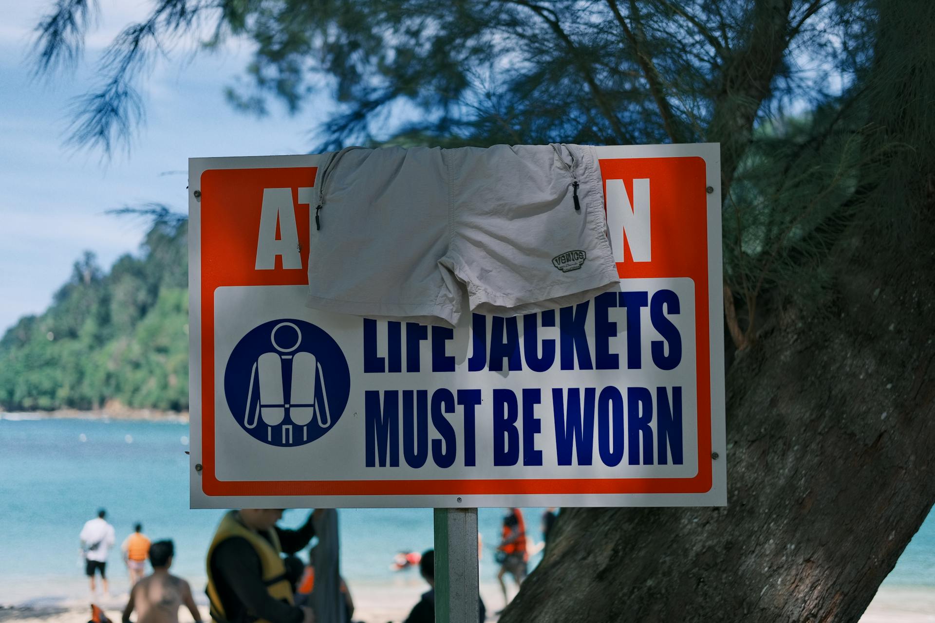 Beach scene with a life jackets warning sign, emphasizing safety during leisure activities.