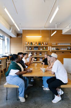 A diverse group of young adults engaged in conversation in a trendy coffee shop setting.