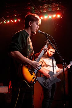 Musicians playing guitars on stage in Szeged, Hungary, under colorful stage lights.