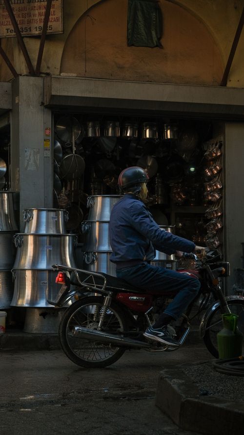 Free A motorbike rider passes by a shop with metal pots. Urban lifestyle and commerce. Stock Photo