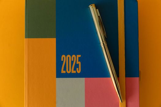 Moderne planner voor 2025 met levendige kleuren en een strakke zilveren pen in een plat ontwerp.