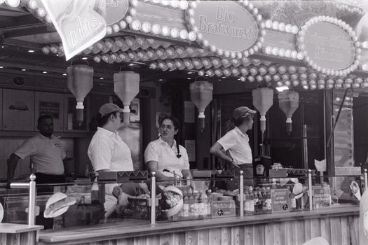 Black and white image of staff working at a food stall during Oktoberfest in Germany.