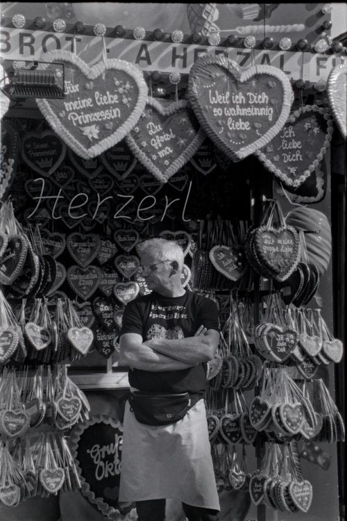 Free Man standing by a gingerbread heart stall at Oktoberfest in Germany. Stock Photo