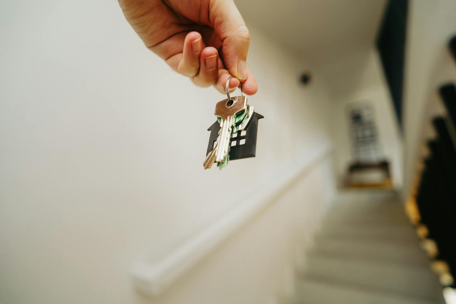 Hand holding door keys new house real estate stairs