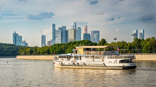 Free A scenic view of Moscow's skyline with a river cruise boat under a blue sky. Stock Photo