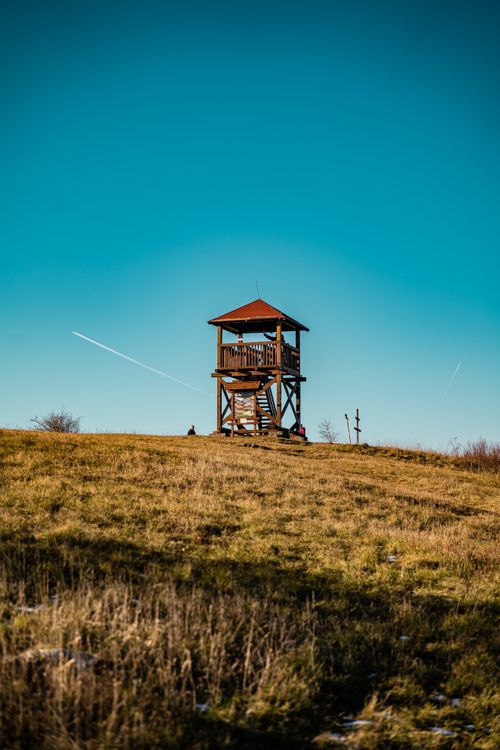 Free Wooden watchtower on grassy hill under a clear blue sky. Stock Photo