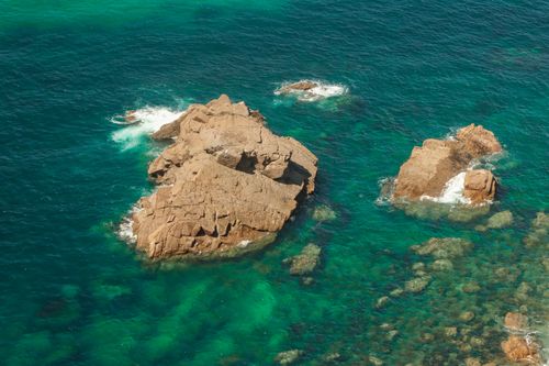 Free A serene aerial shot of rugged rocks in turquoise Atlantic waters near Colares, Lisbon. Stock Photo