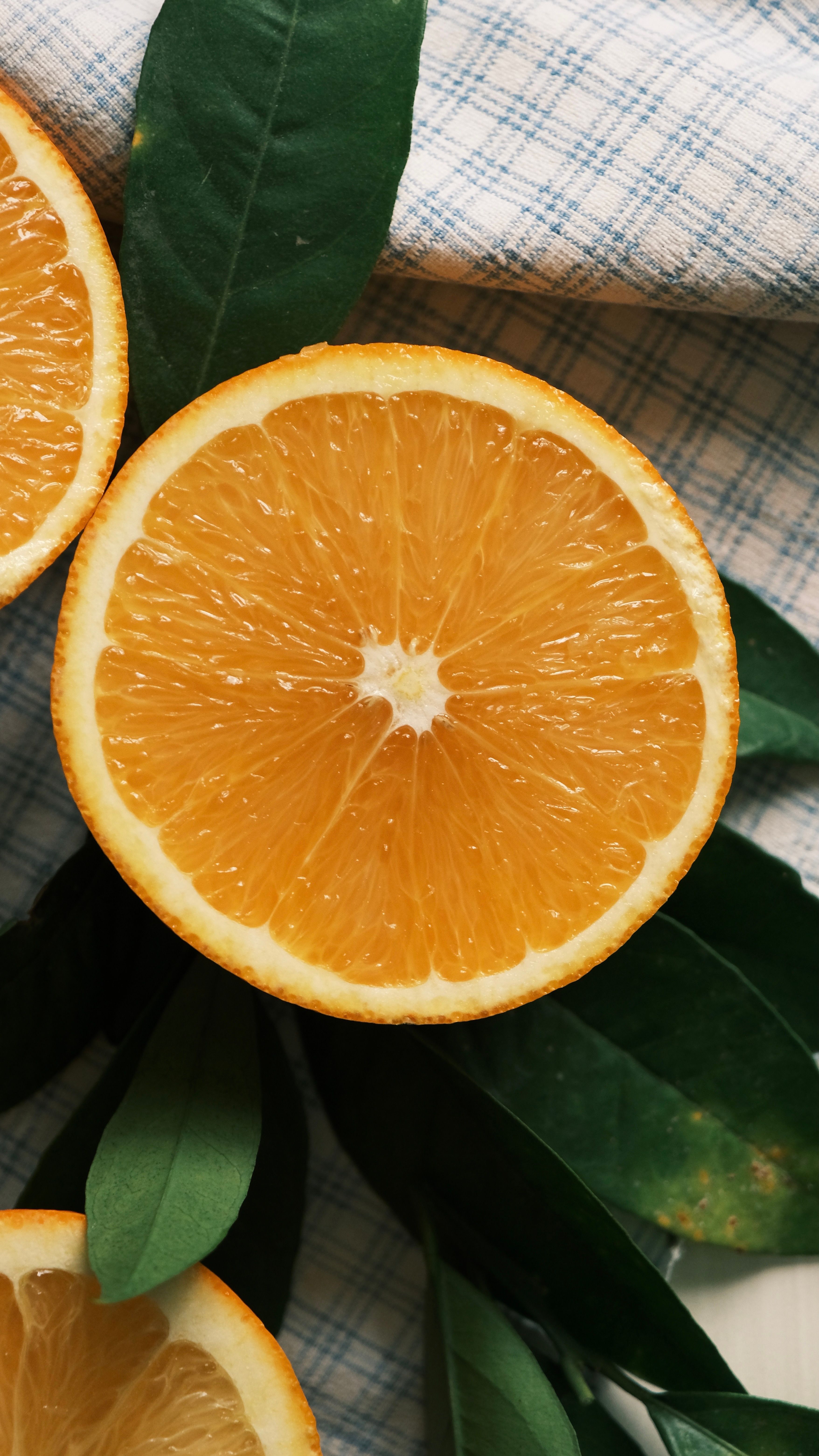 Close-up of juicy orange slices on a green leafy background, ideal for food and health themes.