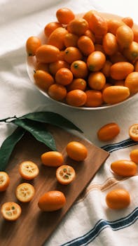 A close-up of fresh kumquats on a wooden board with leaves, showcasing vibrant colors and textures.