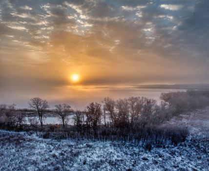 A breathtaking winter sunrise casting warm hues over a frosty, tranquil landscape.