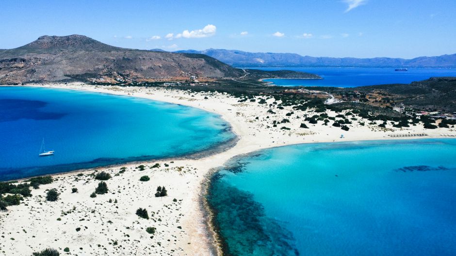 Stunning aerial view of Elafonissi Beach in Greece with crystal-clear turquoise waters and white sands.