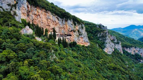 Free Breathtaking aerial view of a monastery nestled in lush greenery and rocky cliffs in Dimitsana, Greece. Stock Photo