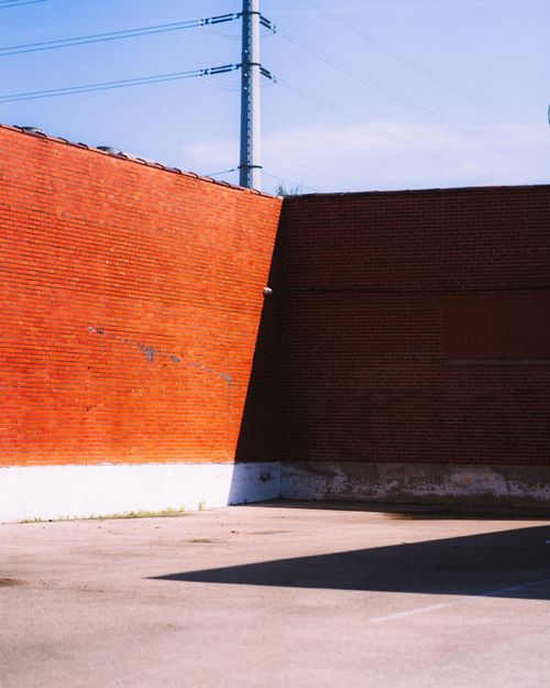 Free Bright red brick wall casting shadows in a Houston parking lot, sunny day. Stock Photo