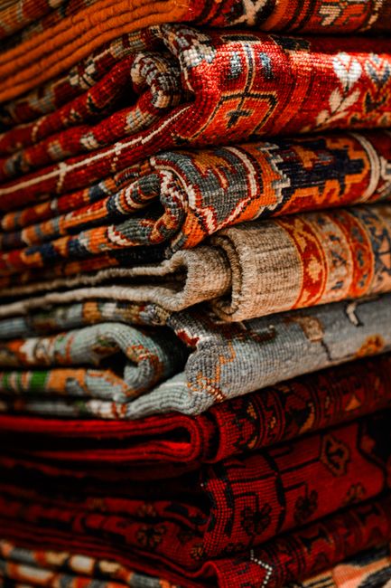 Stack of colorful Persian rugs showcasing intricate designs and textures.