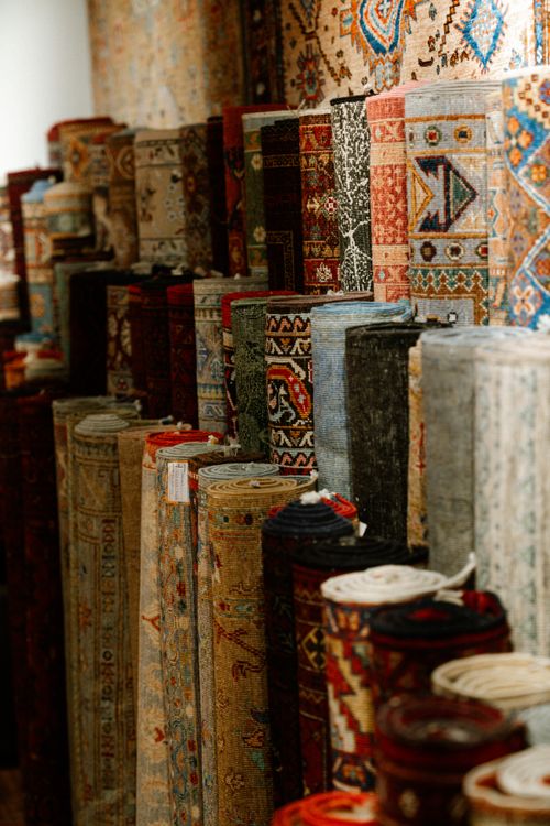 Free A colorful assortment of intricate Persian carpets rolled and displayed indoors, showcasing rich patterns and textures. Stock Photo