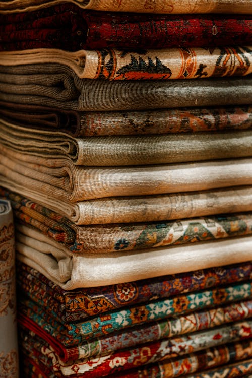 Stack of Ornate Handmade Persian Rugs on Display · Free Stock Photo