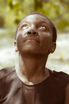 一幅富有洞察力的肖像，描绘了一位女性在宁静的户外环境中向上凝视