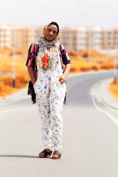 一位时尚女士在阳光明媚的城市道路上自信地摆出姿势，展示着充满活力的服装