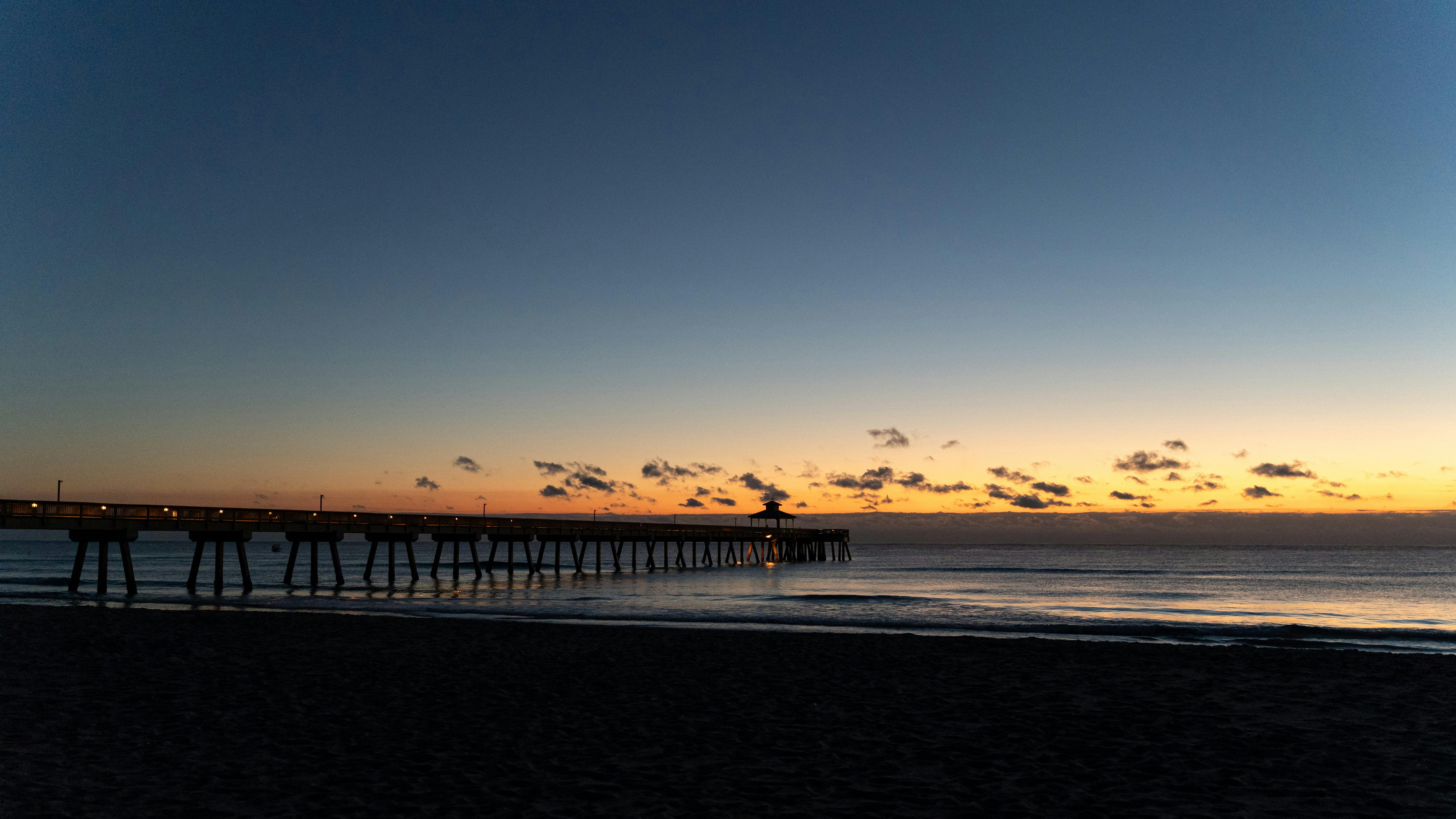 Peaceful sunset view of a silhouette pier stretching into the calm ocean waters.