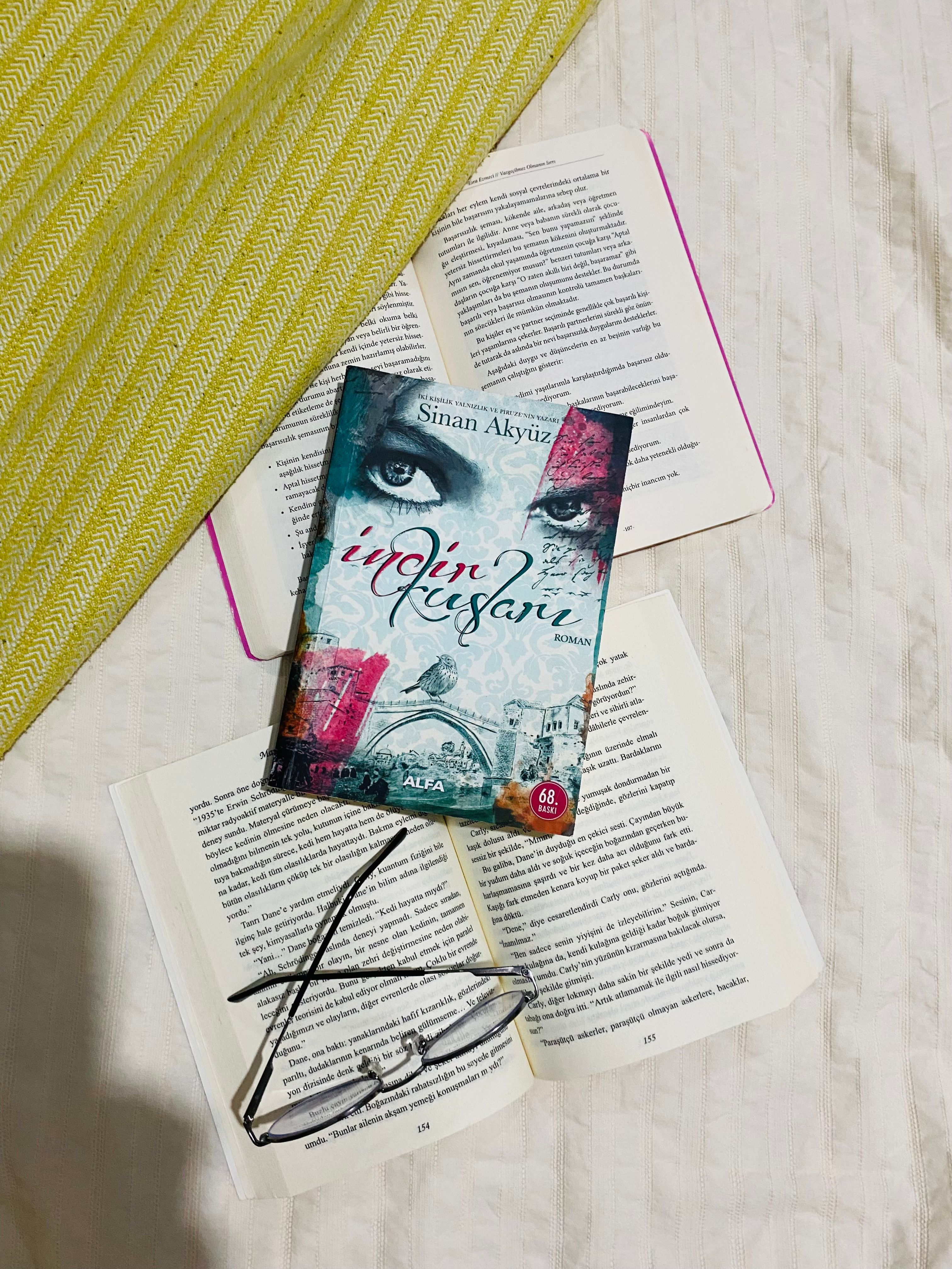Artistic flat lay of open books, a novel, and eyeglasses on a bed.