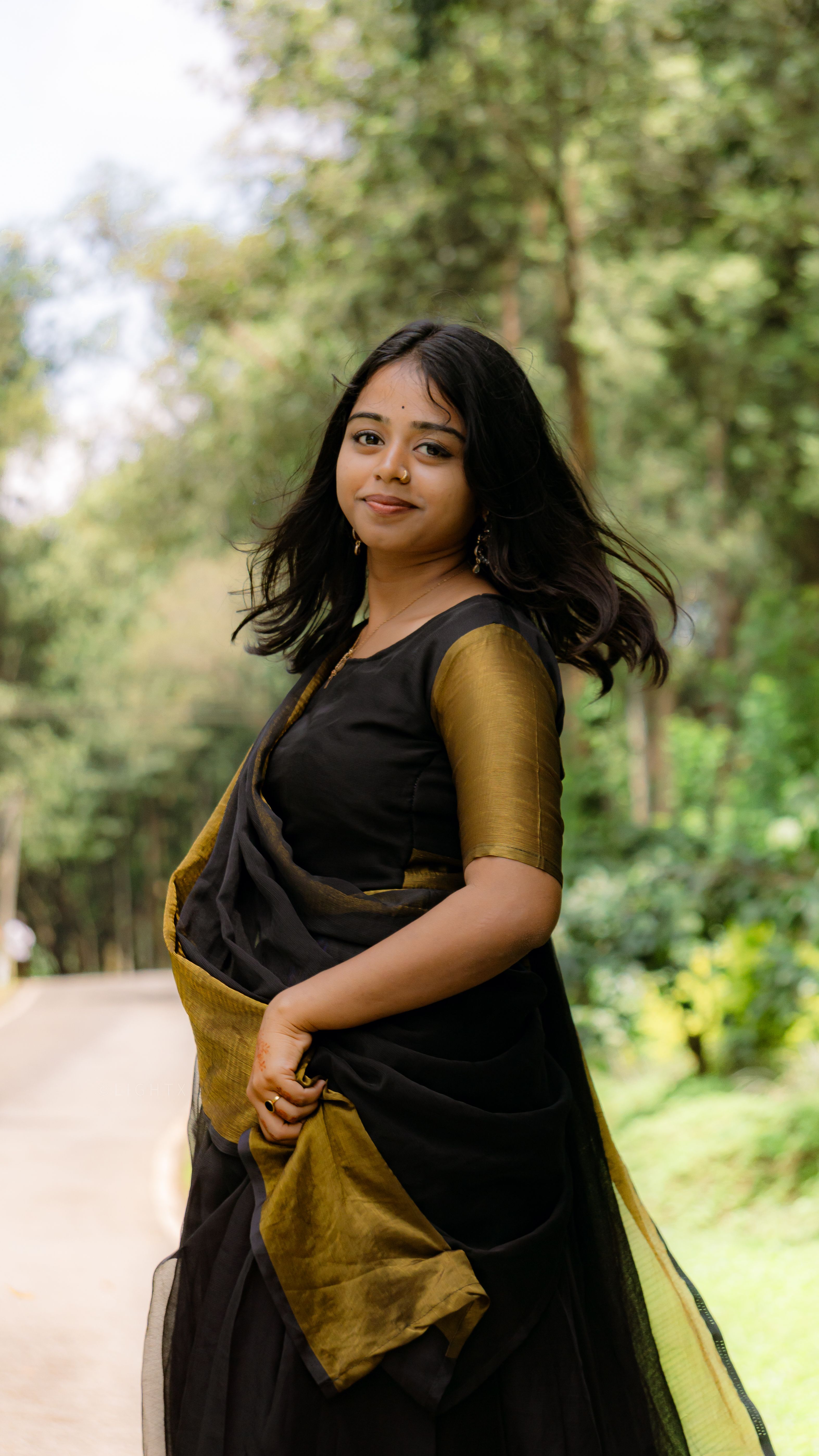 Portrait of a young woman in traditional attire walking outdoors on a sunny day.