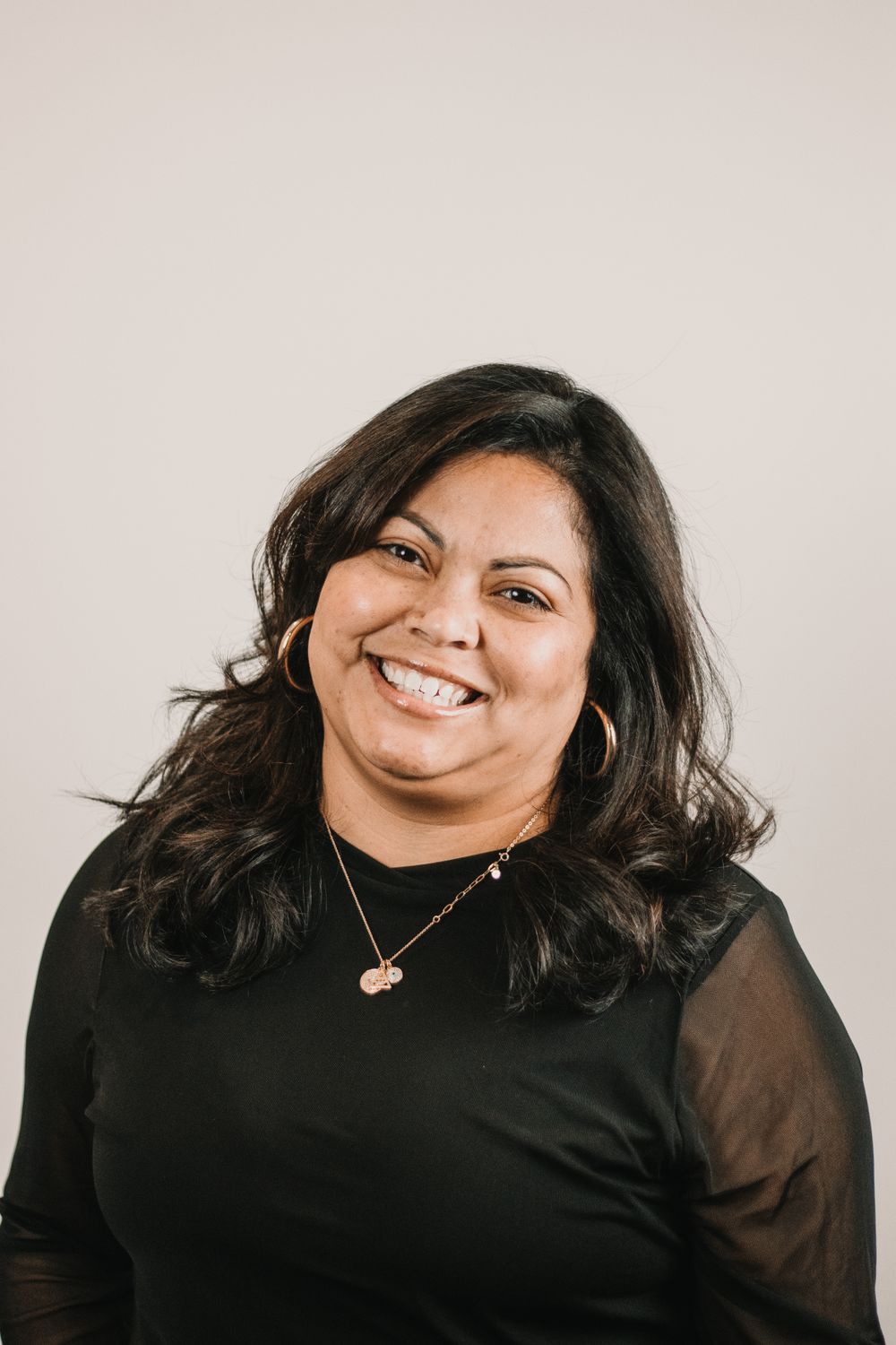 A smiling Tidewater therapist in a black top, seated in a warm office