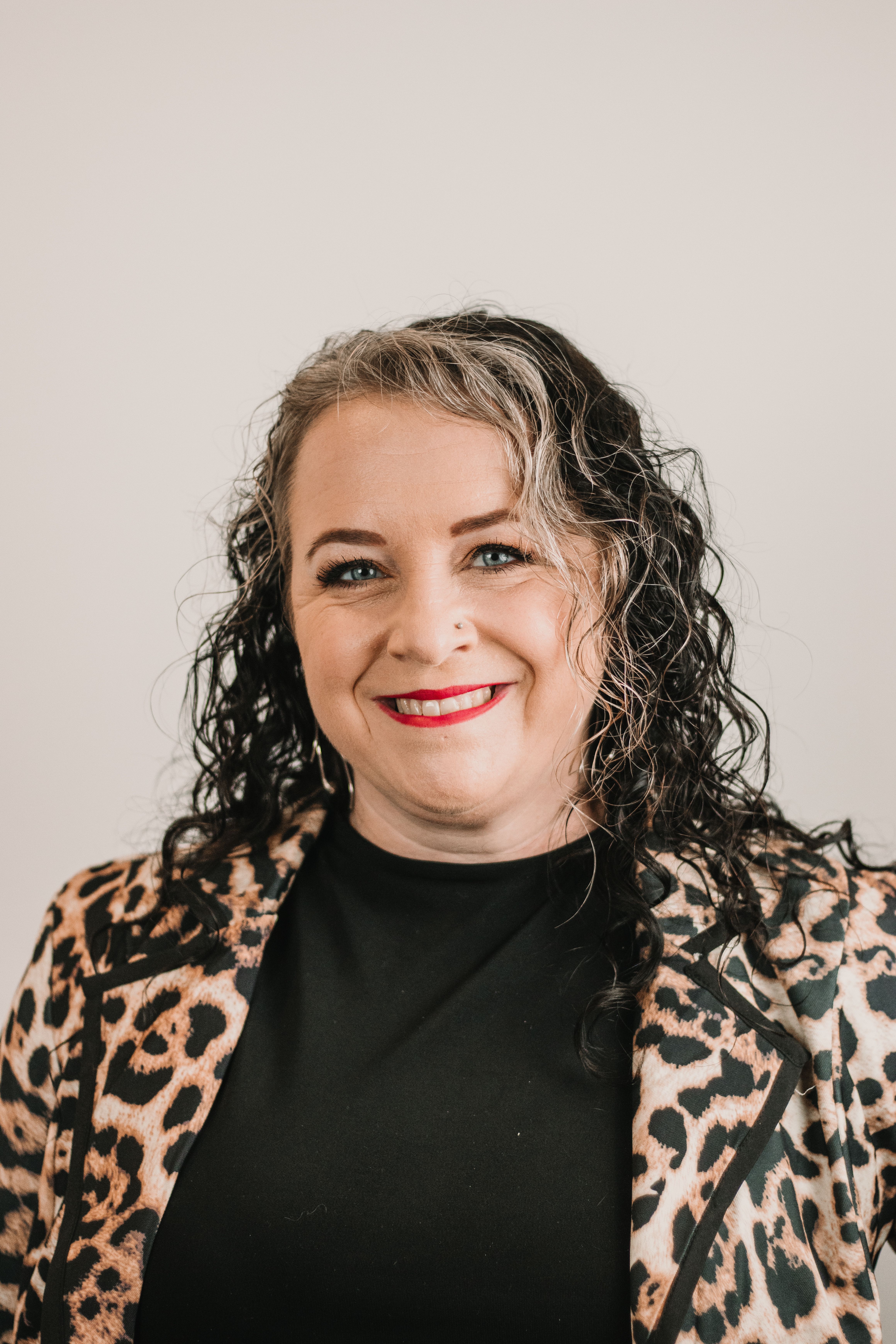 Confident businesswoman in leopard print jacket smiling warmly.