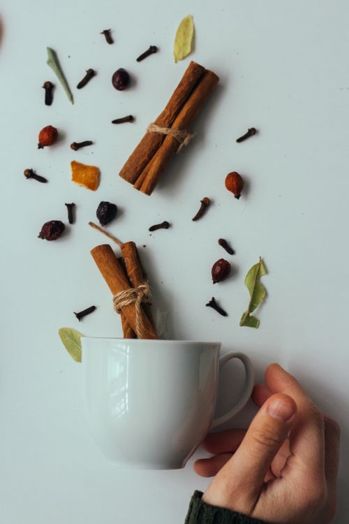 Free Overhead view of a white mug with cinnamon sticks and assorted spices on a white background. Stock Photo