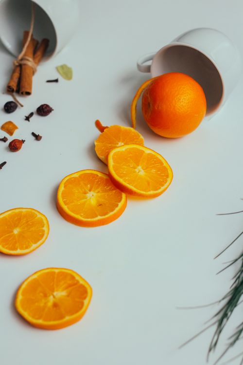 Free Bright and vibrant orange slices with spice ingredients on a white surface. Stock Photo