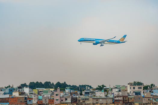 Un aereo della Vietnam Airlines vola sopra la città, mostrando il viaggio aereo sopra le abitazioni urbane.