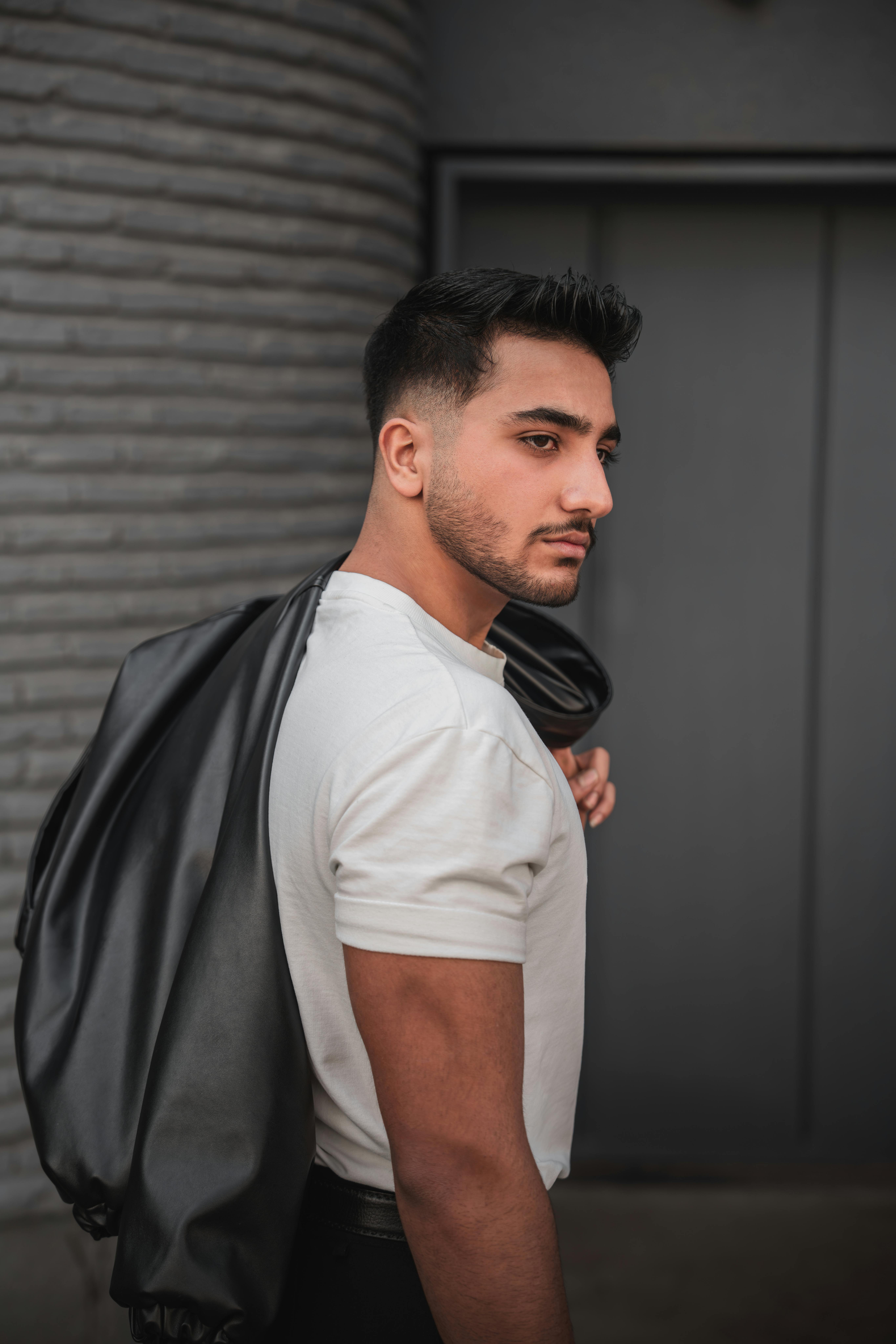 Portrait of a fashionable young man outdoors holding a jacket over his shoulder, exuding confidence.