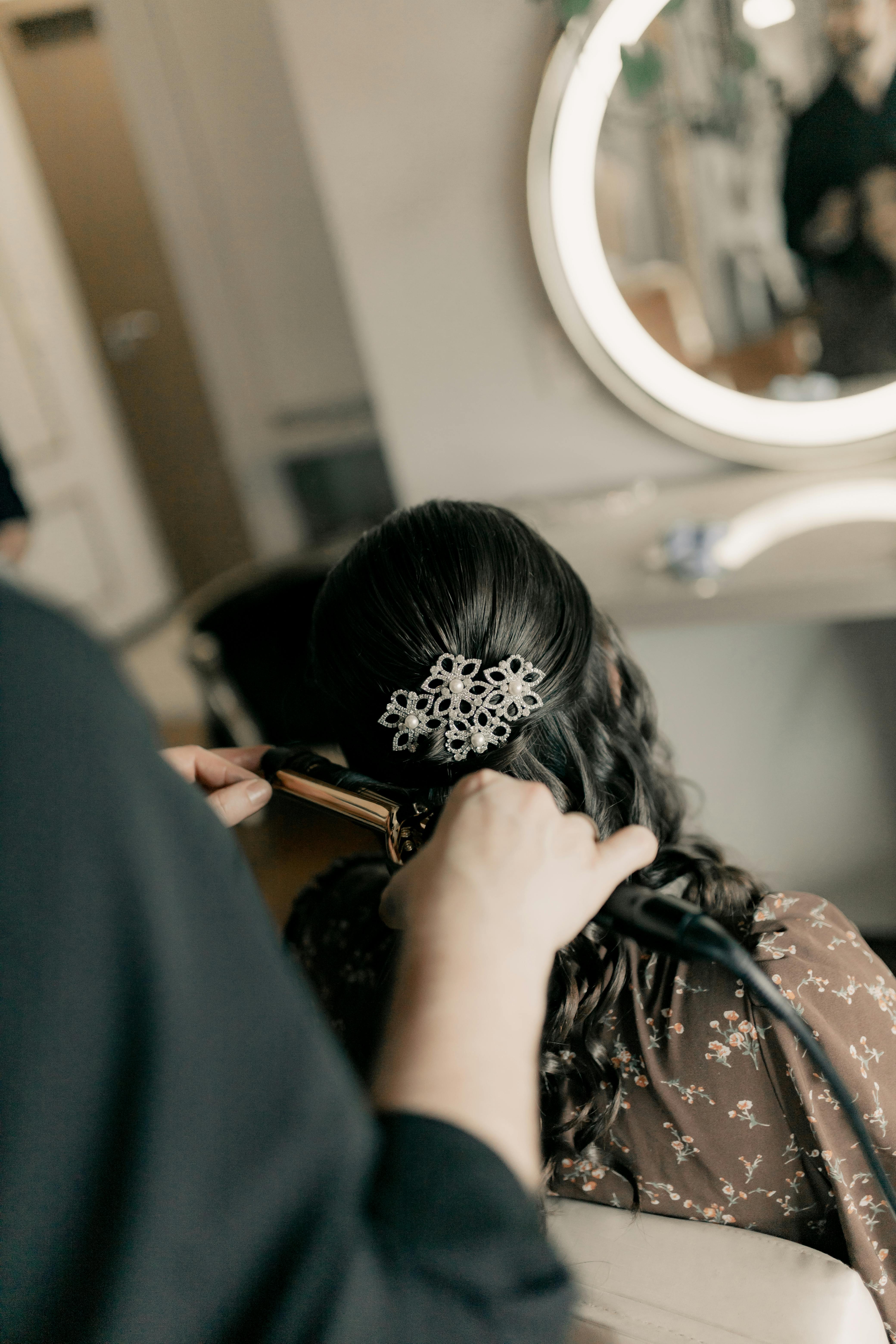 Elegant bridal hair styling with curling iron and intricate hairpiece reflecting glamour.