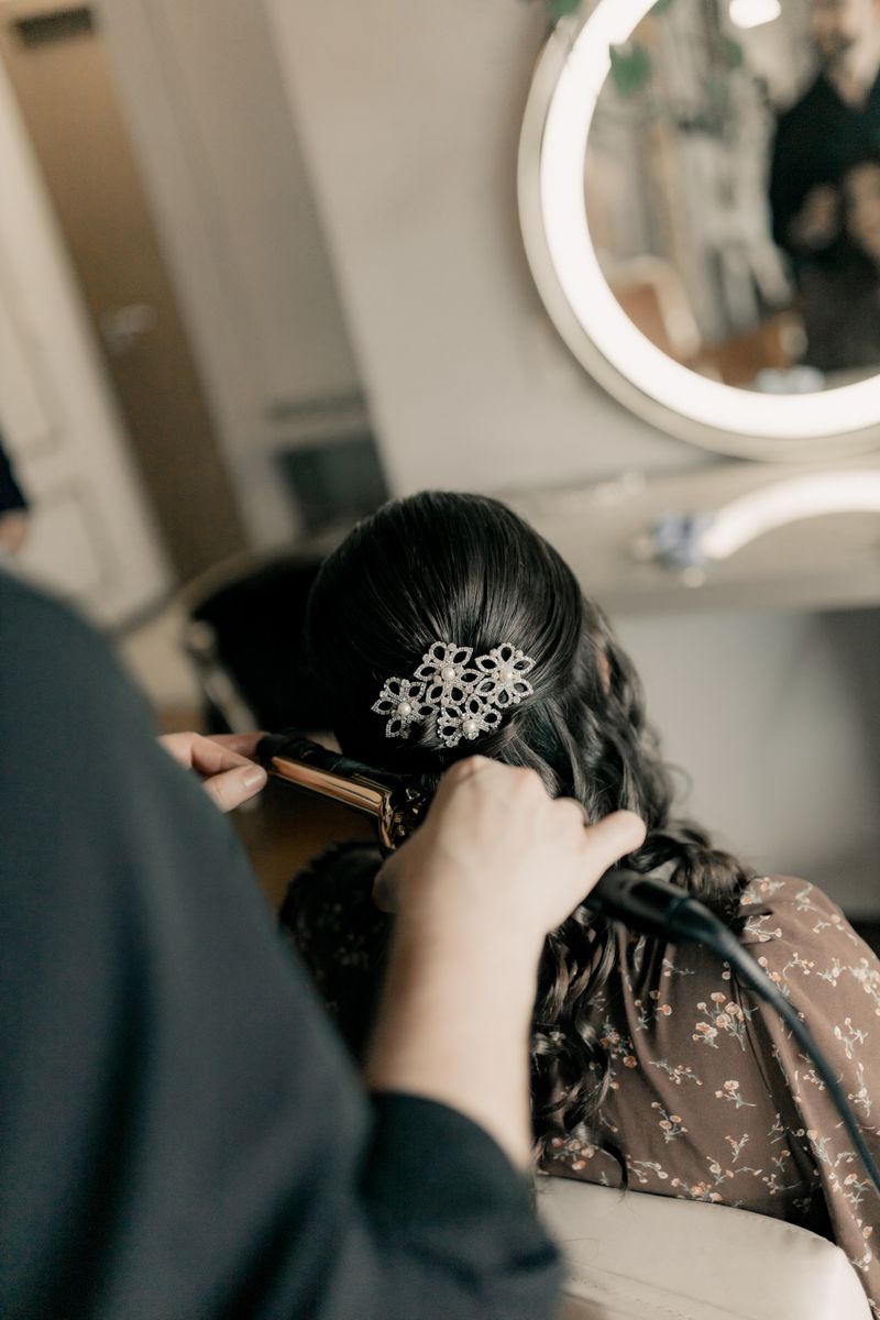 Stylist placing the final pins of a bridal updo with an heirloom hairpiece