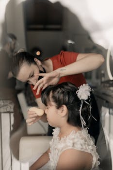 Makeup artist applying foundation on a little girl in preparation for a special occasion.